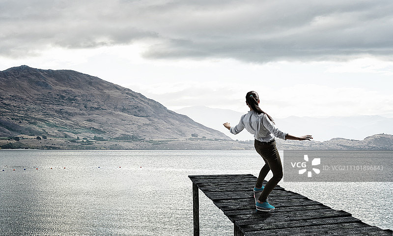 活泼的女孩在木栈桥上滑滑板图片素材