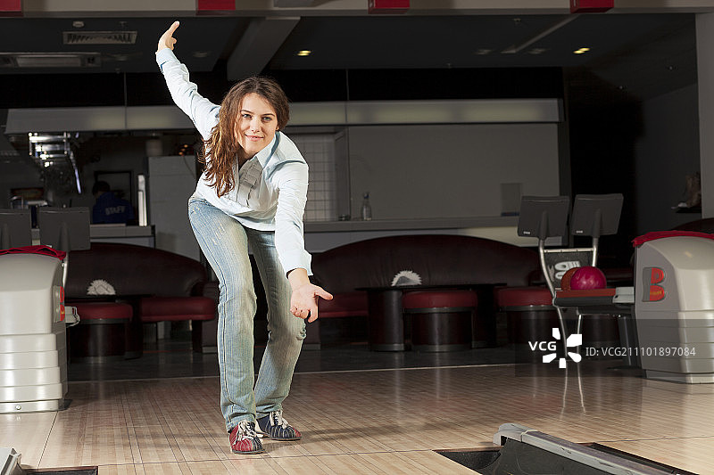 在保龄球俱乐部掷保龄球的年轻漂亮女人图片素材