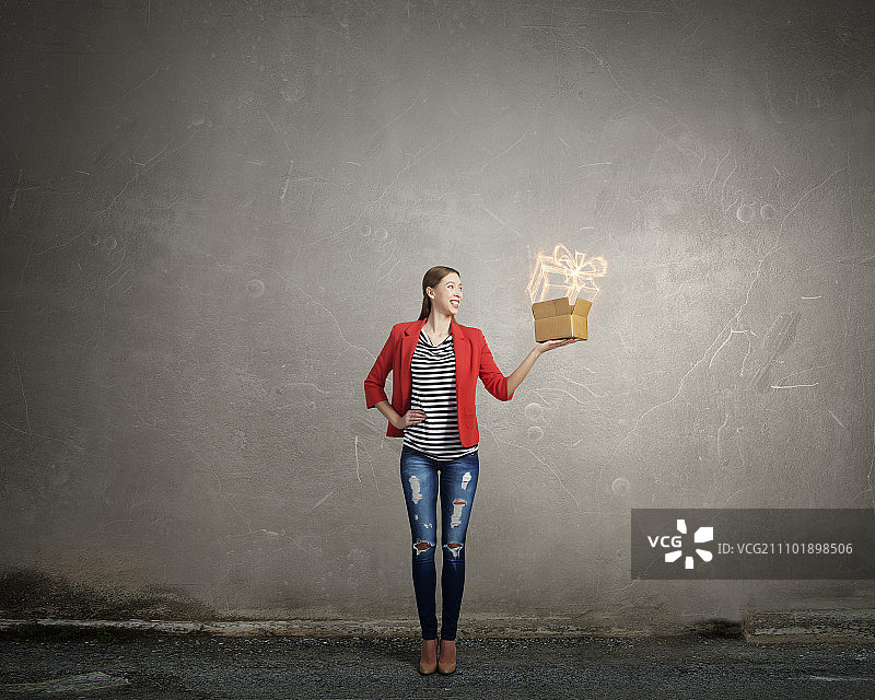 打破常规思维：身穿红色夹克，手拿纸箱的年轻女人图片素材