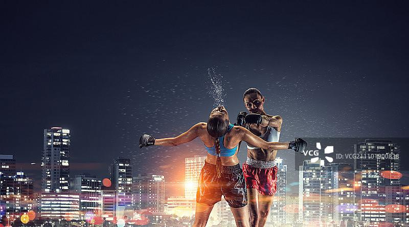 户外女子拳击：两位年轻漂亮的女人在夜景城市背景下拳击图片素材