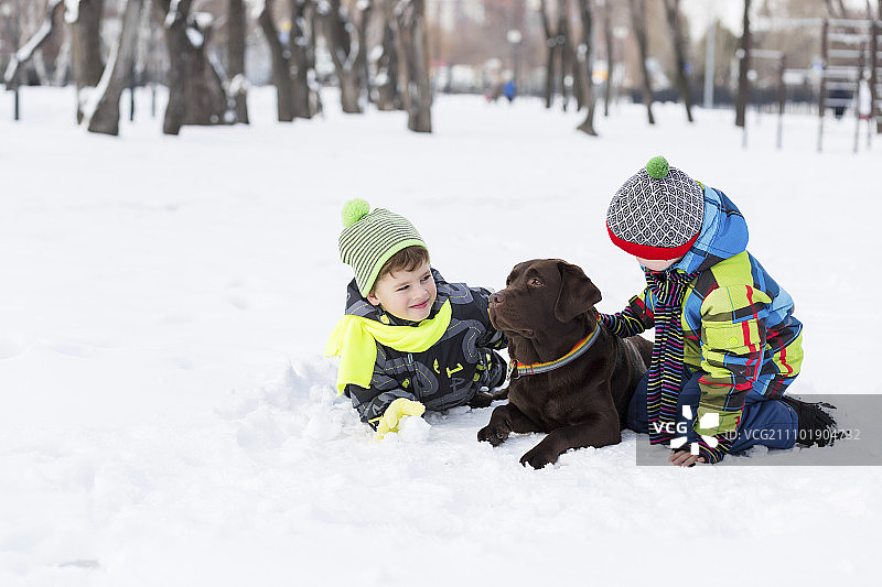 在冬季公园里和狗玩耍的学龄儿童图片素材