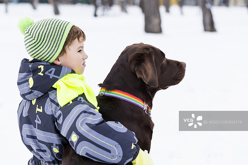 学龄儿童与小狗在冬季公园里，我最好的朋友和我图片素材