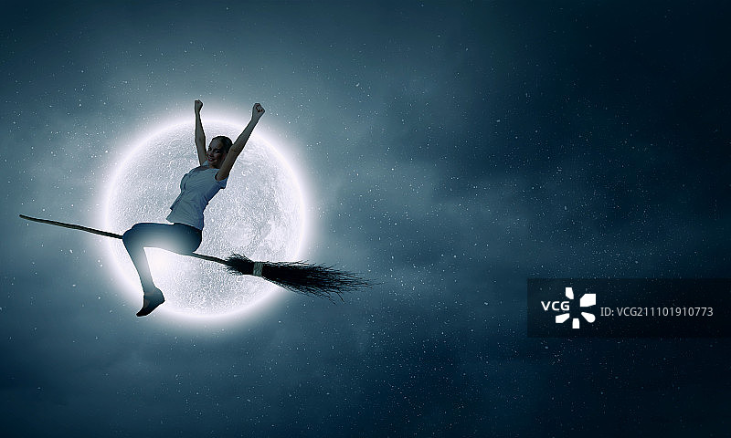 无忧无虑的年轻女子骑着扫帚在空中飞行图片素材