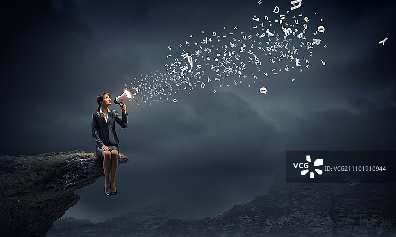拿着扩音器的女商人，年轻女商人坐在岩石边缘用扩音器尖叫图片素材