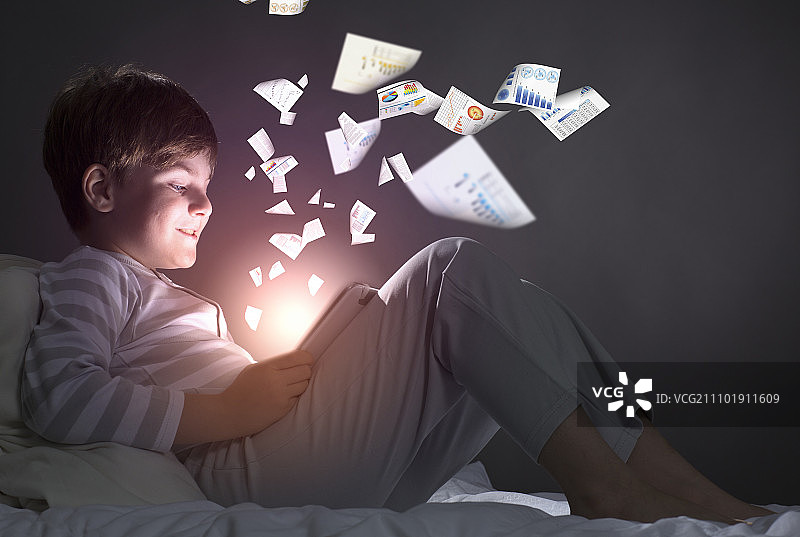 在床上使用平板电脑的可爱小男孩图片素材