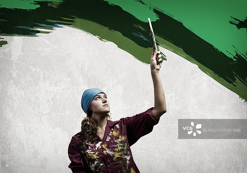 用画笔的妇女：年轻女性用刷子给墙壁上色图片素材