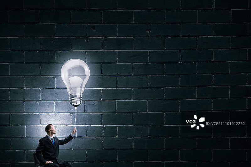 商人拿着灯泡，象征着绝妙的主意图片素材