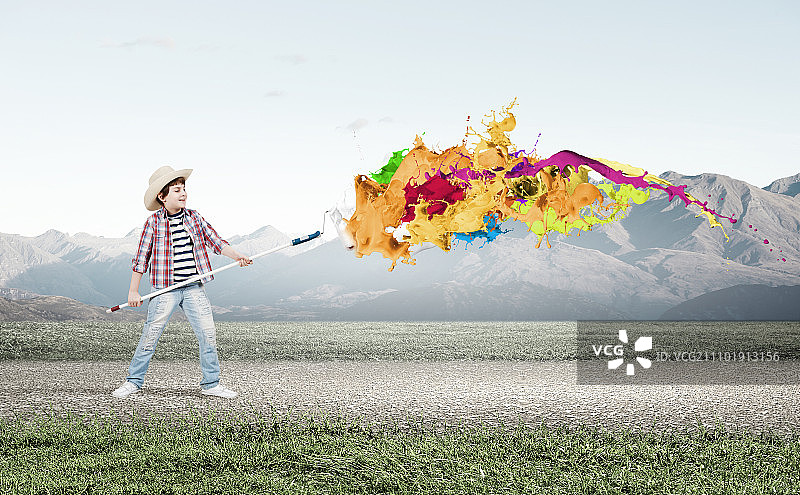 多彩的童年：学龄男孩用刷子在墙上绘画图片素材