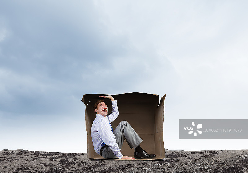 箱子里的男人：被困在小纸箱里的沮丧的年轻商人图片素材