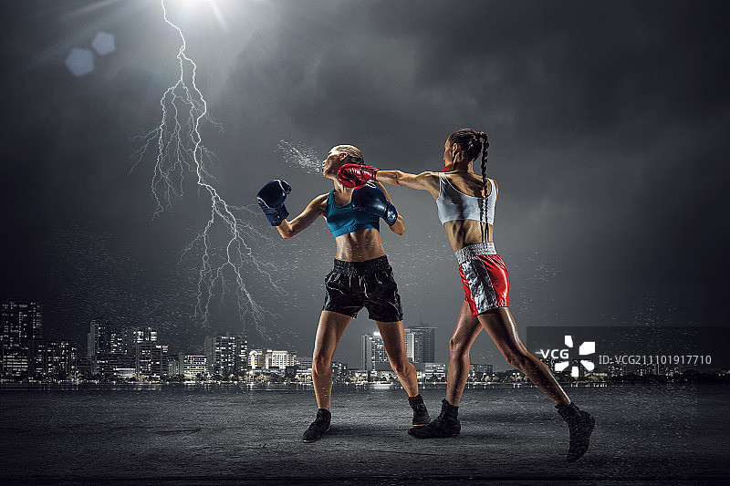 户外女子拳击：两位年轻漂亮的女人在夜景城市背景下拳击图片素材