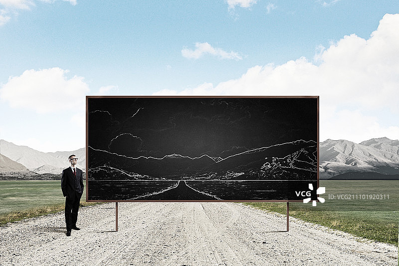 商务研讨会：戴眼镜的年轻商人与带图画的黑板图片素材