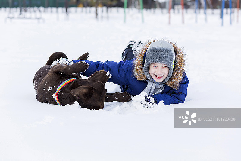 学龄儿童与小狗在冬季公园里，我最好的朋友和我图片素材