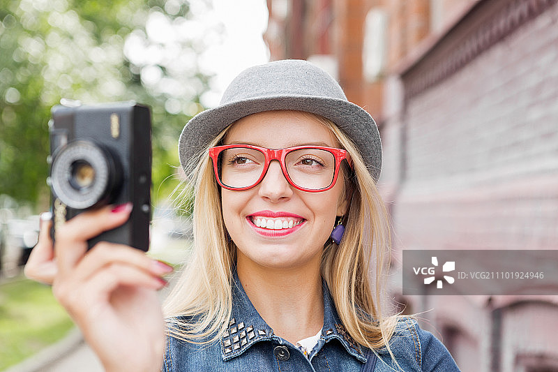 年轻女游客在老城区用相机拍照图片素材