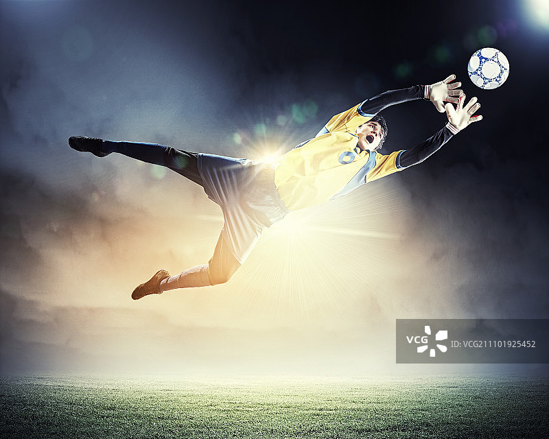 聚光灯下的体育场里，守门员接住了球图片素材