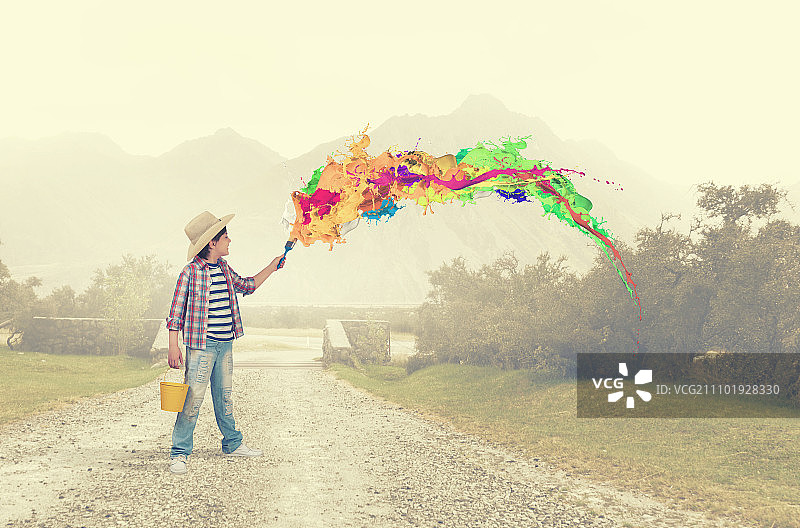 多彩的童年：学龄男孩用刷子在墙上绘画图片素材