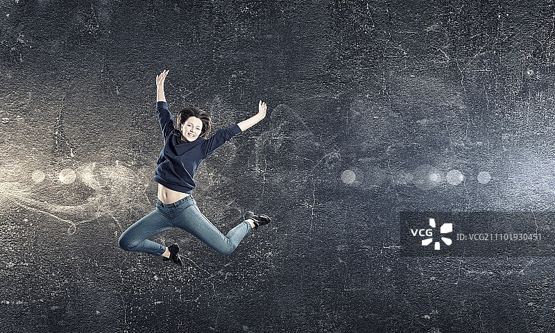 聚光灯下跳跃的年轻女舞者图片素材