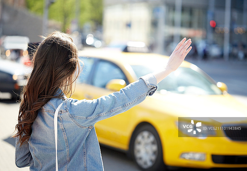年轻女子在城市街道上打车图片素材