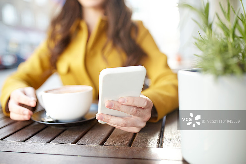通信、科技、休闲与人概念 - 年轻女子或少女在城市街道咖啡馆露台用智能手机发短信和喝可可的特写图片素材