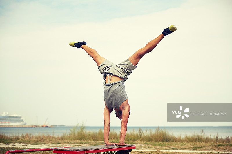 健身运动训练生活方式概念：年轻男子在户外长椅上锻炼图片素材