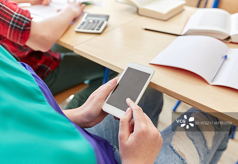 教育：高中学习，使用手机发短信的女学生图片素材