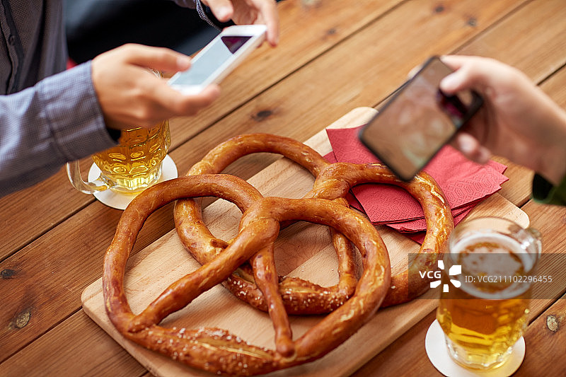 用智能手机拍摄酒吧啤酒和椒盐脆饼图片素材