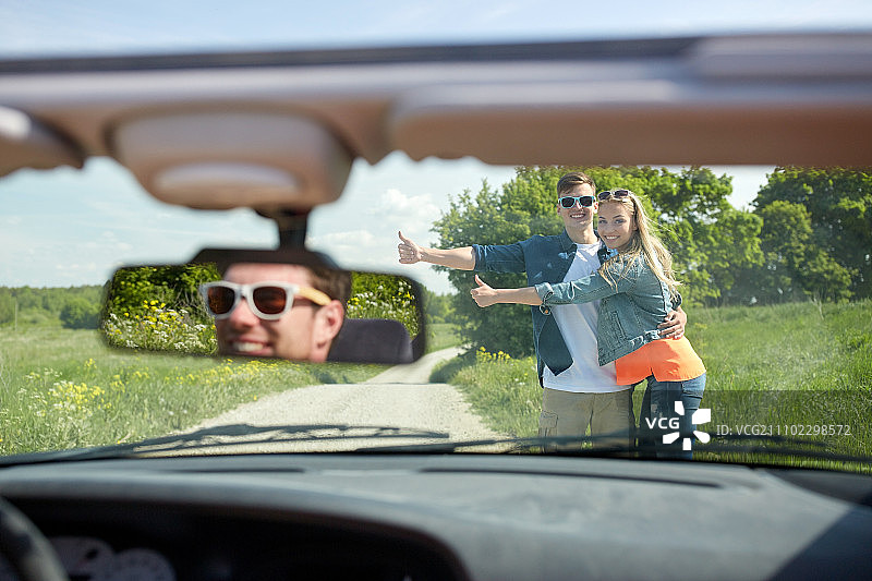 公路旅行搭便车概念：情侣在乡村公路搭车图片素材