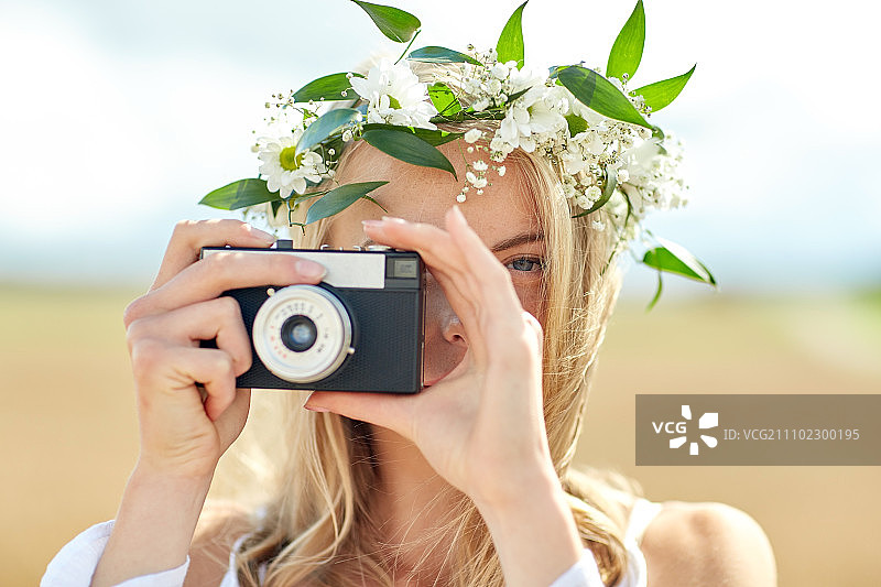 夏季假期概念—戴花环的快乐女人用胶片相机拍照特写镜头图片素材
