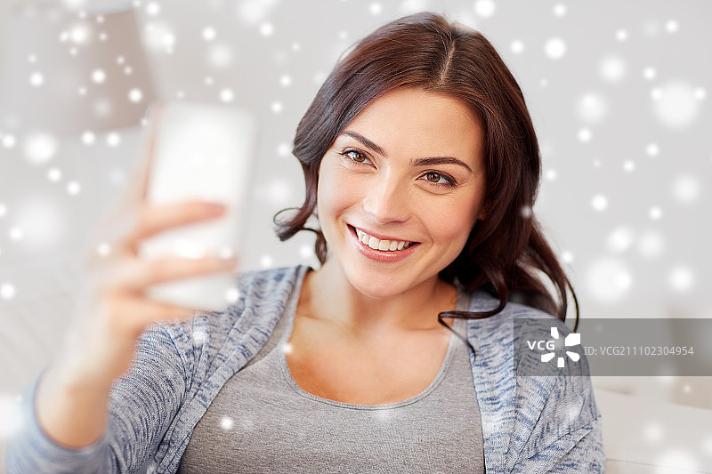 冬季圣诞节：快乐女子在家用智能手机自拍图片素材