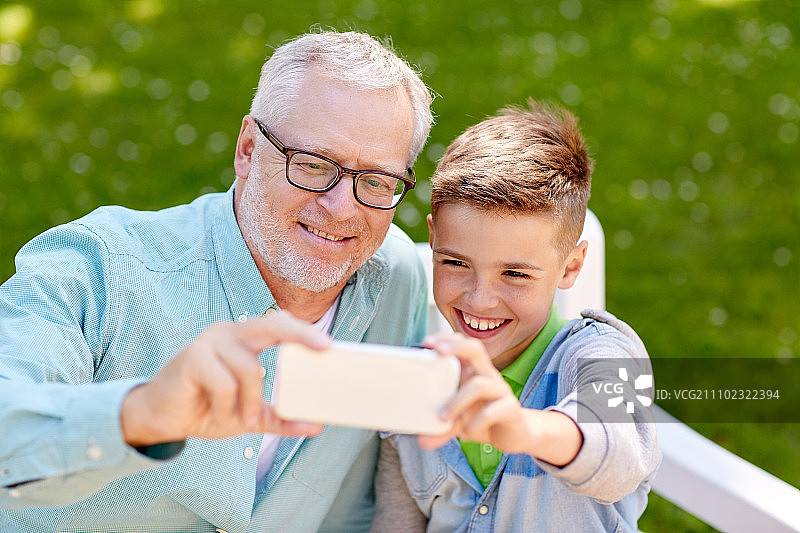 爷爷和孙子在夏季公园用智能手机自拍图片素材