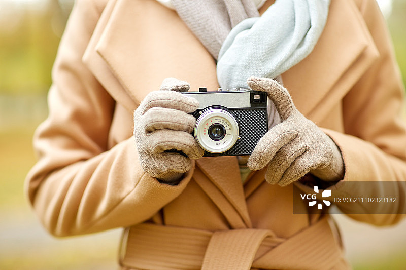 秋季公园里的年轻女性用老式相机拍照图片素材