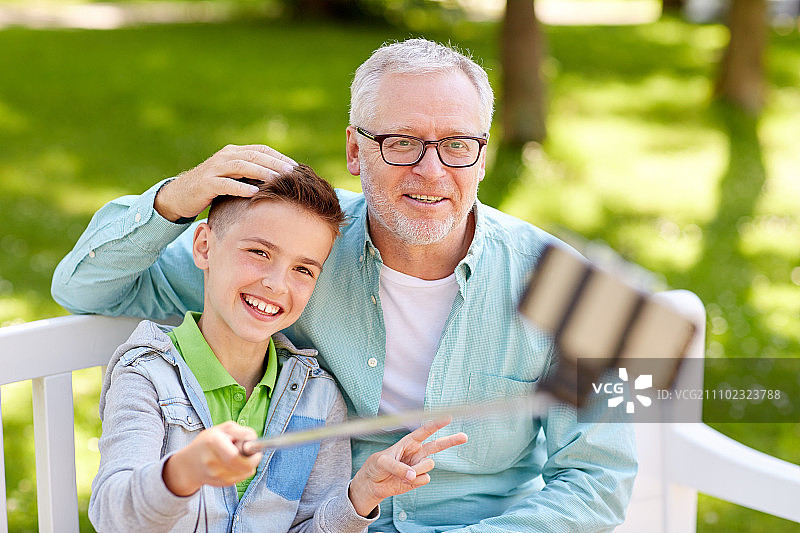 夏日公园里祖孙俩用自拍杆快乐地合影图片素材