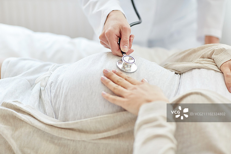 医院里，产科医生用听诊器听孕妇的胎心图片素材