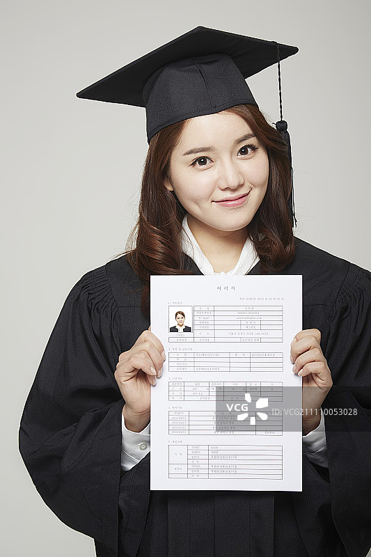 戴毕业帽和穿毕业袍，手拿简历的女人图片素材