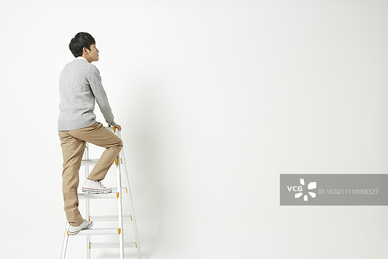 男孩站在梯子上，向远处望去图片素材