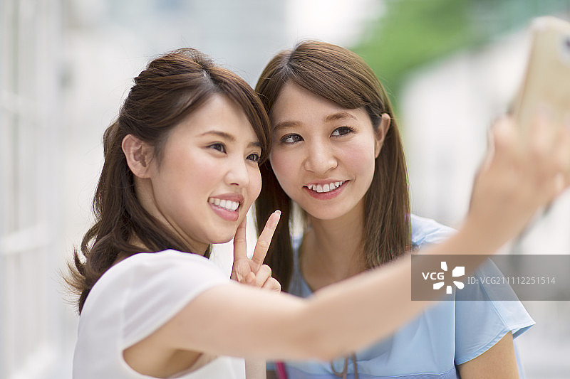 两位女士用智能手机拍照图片素材