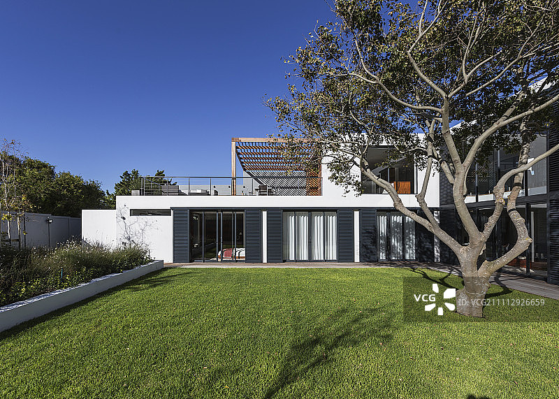 阳光明媚的现代豪华住宅外观，带树木图片素材