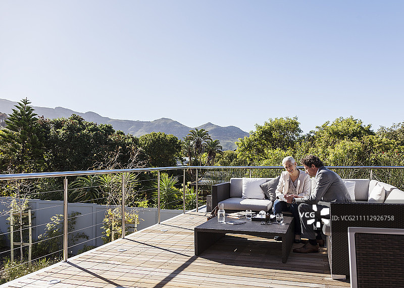 商务人士在阳光明媚的豪华阳台沙发上工作图片素材