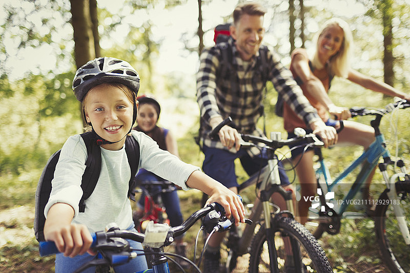 微笑的女孩与家人在树林里骑山地自行车图片素材