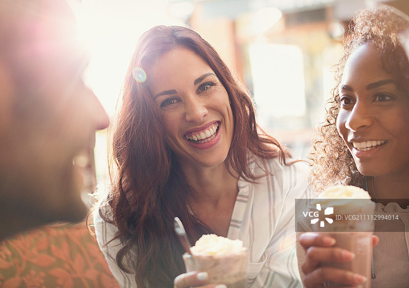 与朋友一起喝奶昔的热情年轻女子特写图片素材