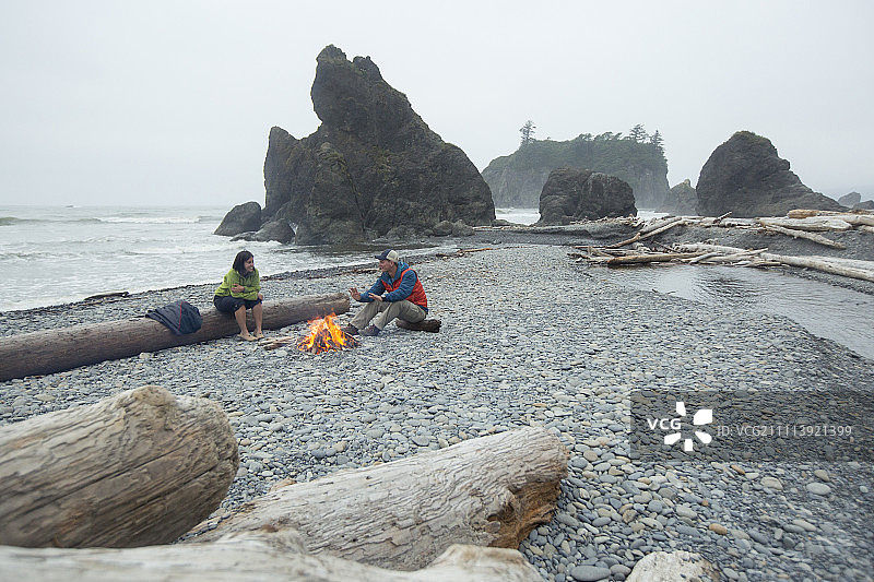 两名徒步旅行者在太平洋西北部的海滩上享受篝火图片素材