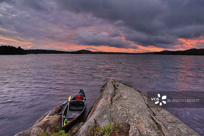 日落时分停靠在洛伊斯湖岩石旁的皮划艇图片素材