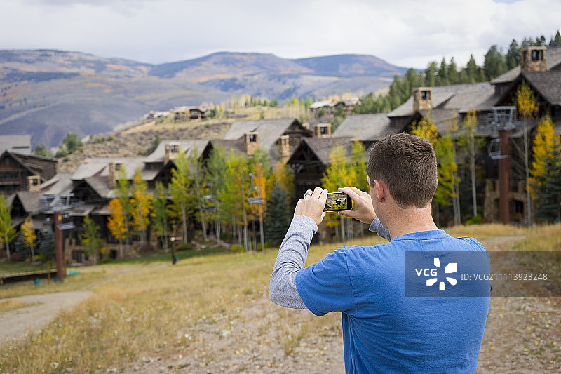 男人用智能手机拍摄秋景照片图片素材