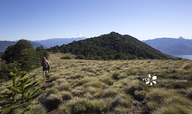 一对徒步旅行者在阿尔卑斯山脊上，身后是火山图片素材