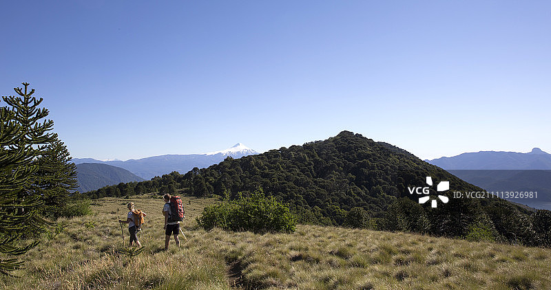 一对徒步旅行者在阿尔卑斯山脊上，身后是火山图片素材