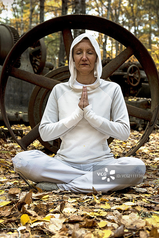 女瑜伽教练在树林中靠近旧机械的地方冥想图片素材