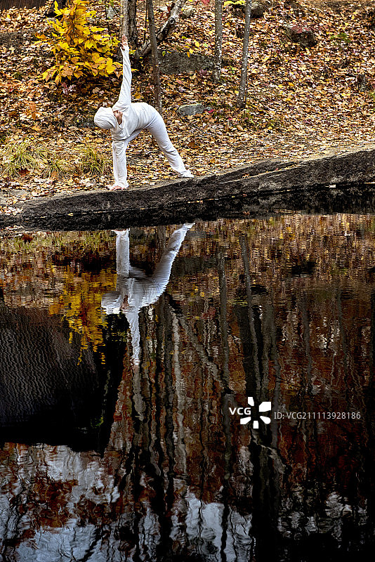 秋天，一位女性在池塘边做瑜伽图片素材