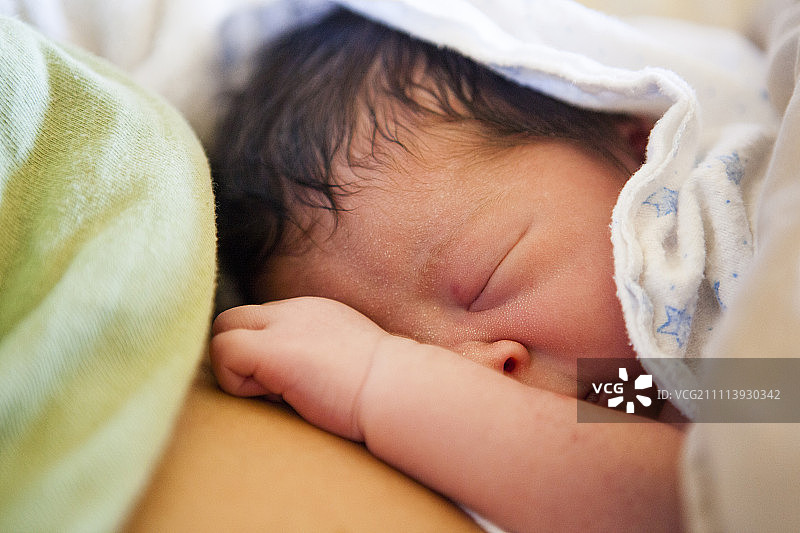 新生女婴在母亲怀里放松的特写图片素材