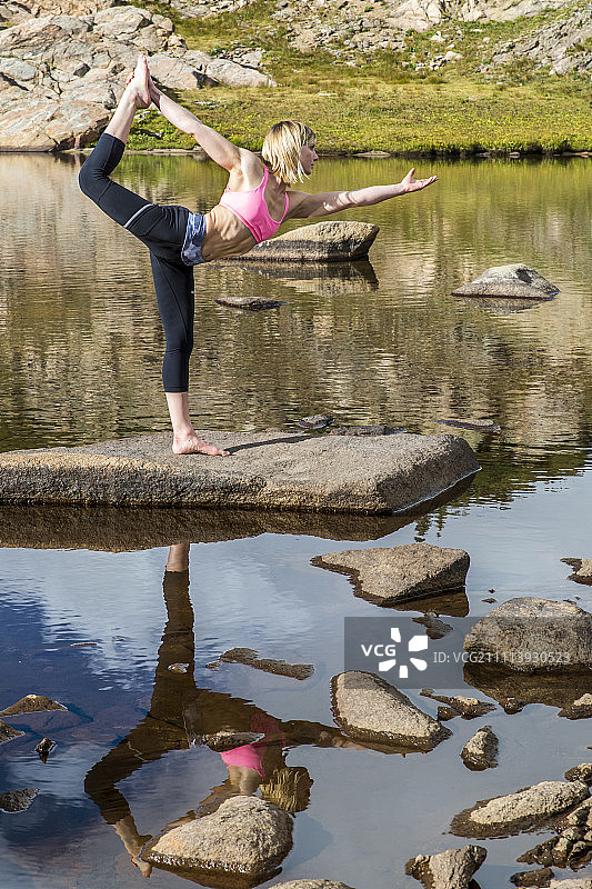年轻女运动员在湖上练习瑜伽图片素材