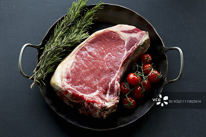 平底锅里的带骨牛肉、樱桃番茄和迷迭香图片素材