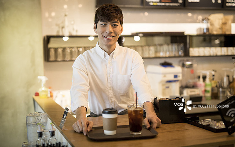 微笑的咖啡师端着一杯咖啡图片素材